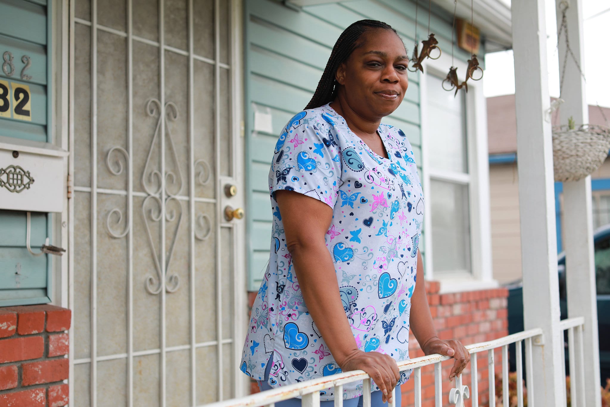 An Abundance Living caregiver in scrubs standing on the front porch of a client's home